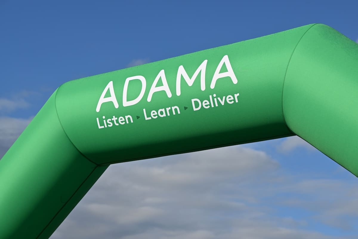 adama-inflatable-arch-close-up Close-up of the ADAMA green inflatable entrance arch with 'Listen, Learn, Deliver' tagline.