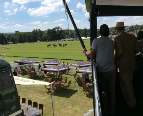 Guests watching a polo match from a hospitality structure balcony overlooking Jaeger-LeCoultre branded pitch-side seating