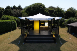 hexis-single-storey-bar-structure-garden Single-storey HEXIS structure with yellow bar feature and white canopy roof in a garden setting.