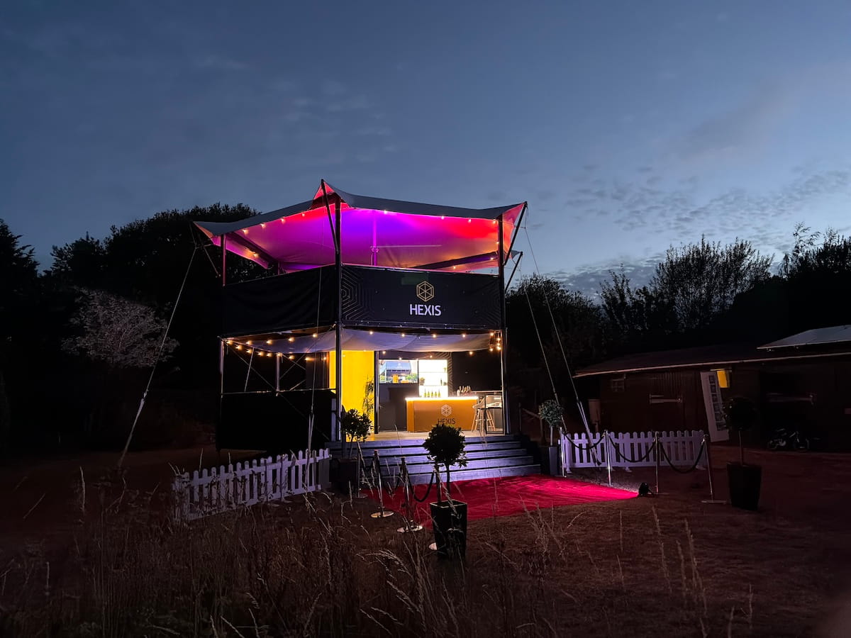 hexis-structure-dusk-pink-purple-lighting HEXIS elevated hospitality structure at dusk with pink and purple canopy lighting and illuminated red carpet.