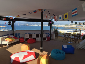 Interior of a HEXIS VIP hospitality lounge overlooking a marina with seating, tables and branded event decor