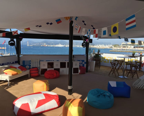 Interior of a HEXIS VIP hospitality lounge overlooking a marina with seating, tables and branded event decor