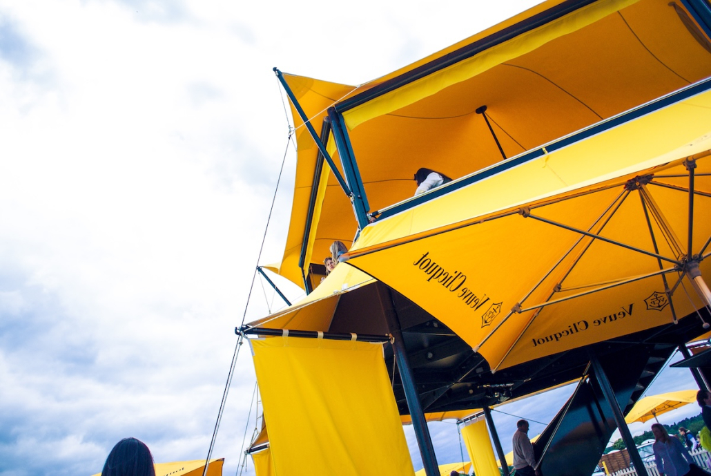 veuve-clicquot-yellow-canopy-structure-low-angle Low angle view of the Veuve Clicquot branded yellow canopy hospitality structure with guests on the upper deck